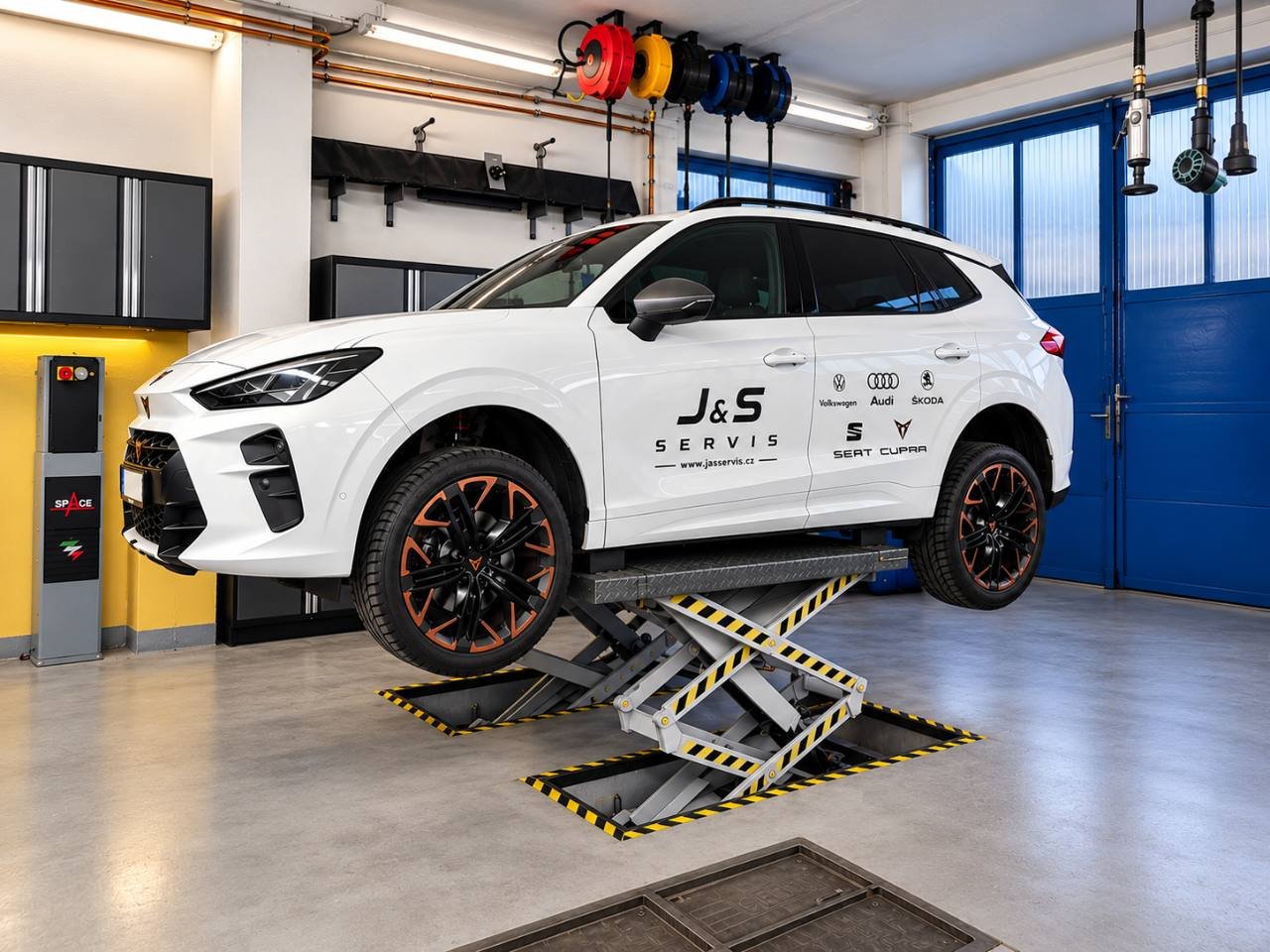 Bílá CUPRA J&S SERVIS na zvedáku v servisní dílně