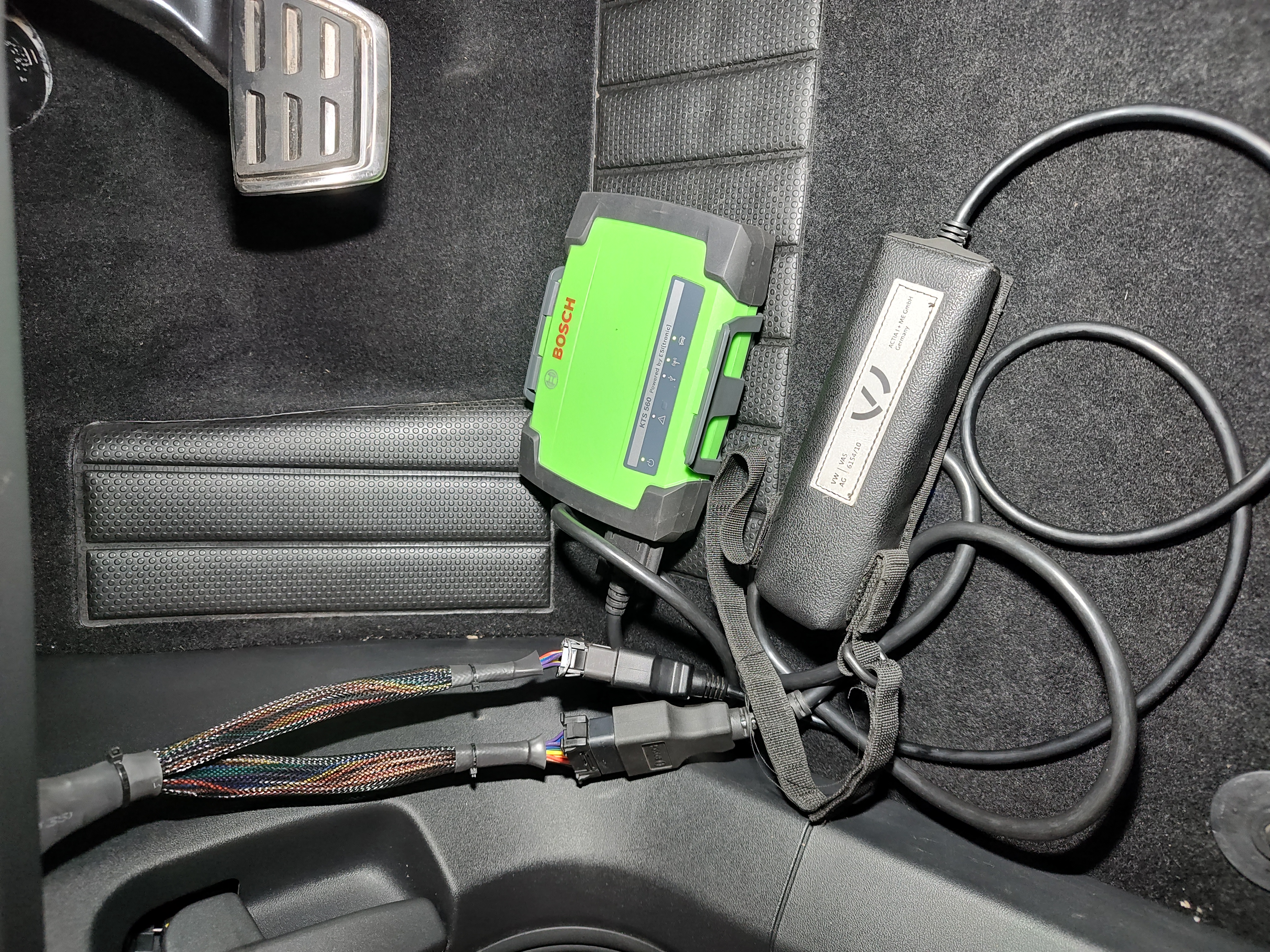 Bosch KTS and VAS diagnostic interfaces with wiring in the driver's compartment of the Škoda Enyaq car.