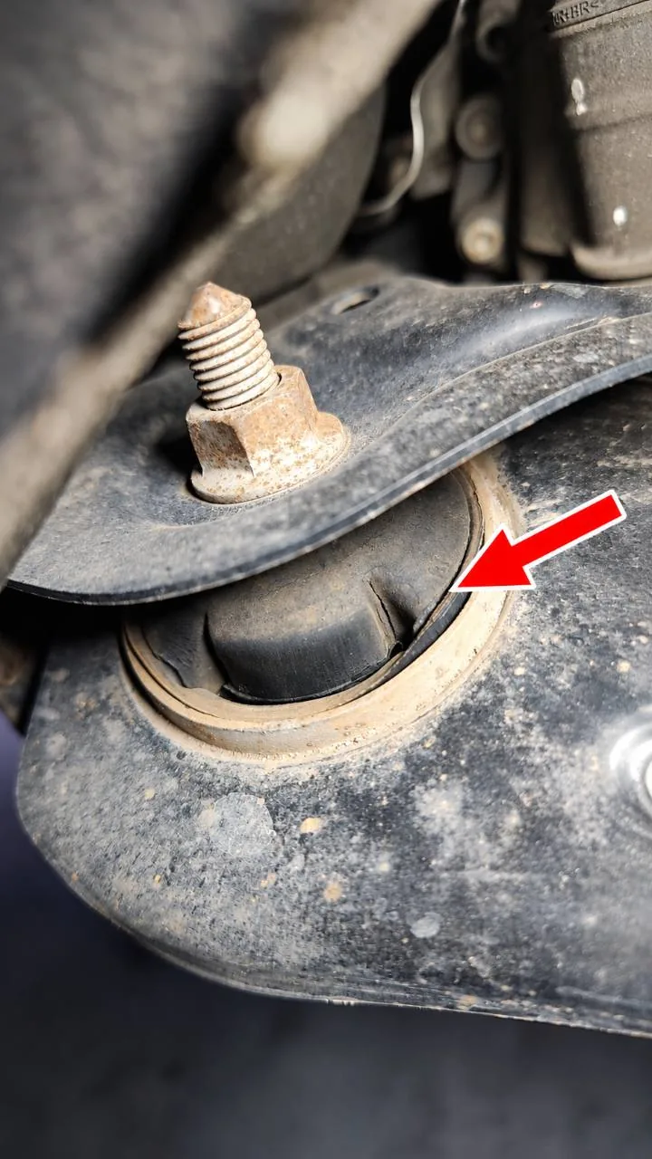 Detail eines gerissenen Fahrwerks-Gummilagers mit rotem Pfeil an der Schadstelle.